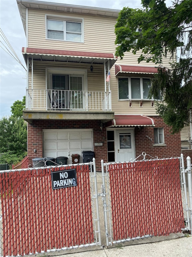 1455 Kennellworth Pl, Bronx, NY 10465 - view of front facade with a balcony, a garage, a fenced front yard, and brick siding