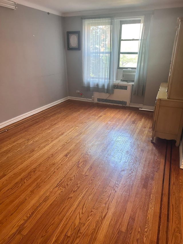 118-14 83rd Ave Unit 2E, Kew Gardens, NY 11415 - spare room featuring radiator heating unit, wood finished floors, and cooling unit