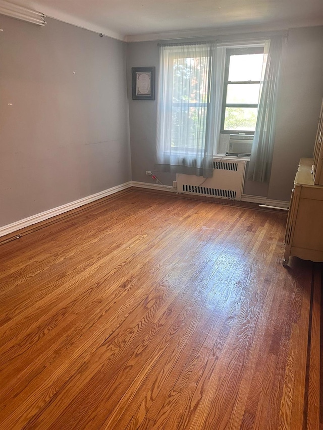 118-14 83rd Ave Unit 2E, Kew Gardens, NY 11415 - empty room with radiator, wood finished floors, and cooling unit