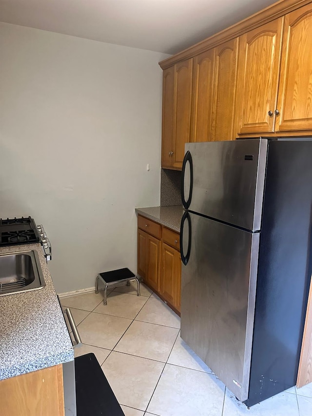 118-14 83rd Ave Unit 2E, Kew Gardens, NY 11415 - kitchen with freestanding refrigerator, light tile patterned floors, and brown cabinets
