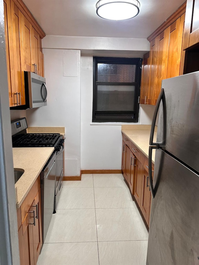 6145 98th St Unit 5J, Rego Park, NY 11374 - kitchen with stainless steel appliances, brown cabinetry, light tile patterned flooring, and light stone counters