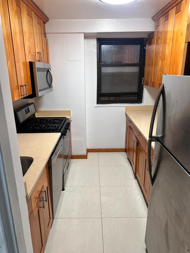 6145 98th St Unit 5J, Rego Park, NY 11374 - kitchen featuring stainless steel appliances, brown cabinetry, light tile patterned floors, and light stone countertops
