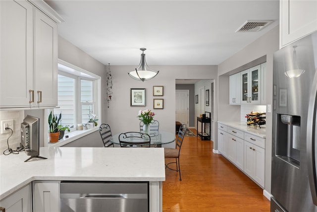 15 Shadetree Ln, Stony Brook, NY 11790 - kitchen featuring appliances with stainless steel finishes, light wood-style flooring, white cabinetry, decorative backsplash, and glass insert cabinets