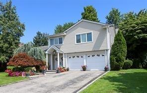 27 Brookfield Rd, Manhasset Hills, NY 11040 - view of front of property featuring an attached garage, asphalt driveway, and a front lawn