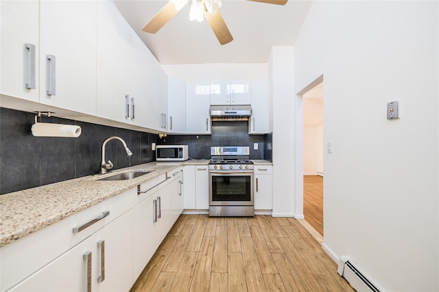 3-06 121st St, College Point, NY 11356 - kitchen with stainless steel range with gas cooktop, a baseboard radiator, under cabinet range hood, light wood finished floors, and ceiling fan