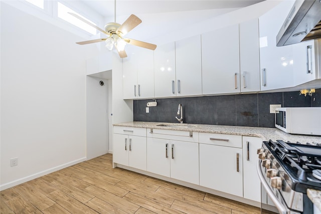 3-06 121st St, College Point, NY 11356 - kitchen with exhaust hood, white microwave, stainless steel gas range, white cabinetry, and backsplash
