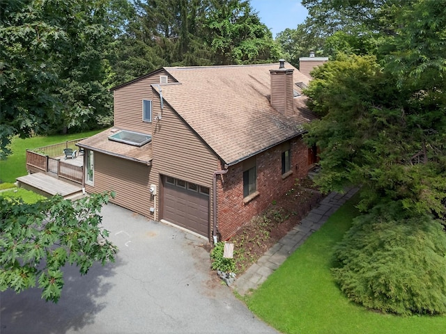 53 Mountain View Dr, Holmes, NY 12531 - view of front of home with driveway, a chimney, a deck, brick siding, and a garage