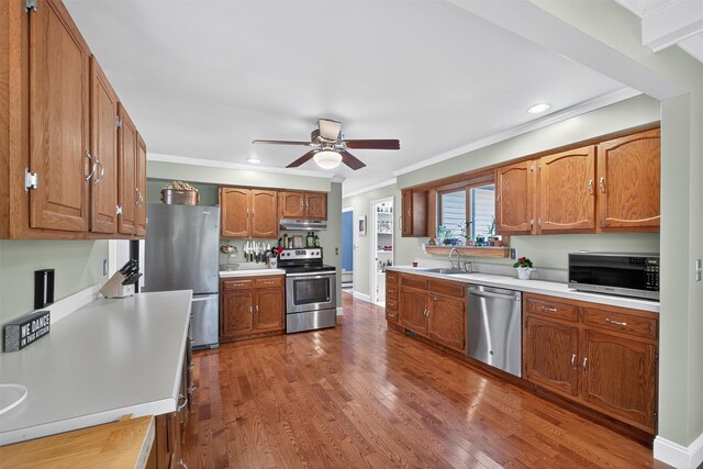 53 Mountain View Dr, Holmes, NY 12531 - kitchen featuring appliances with stainless steel finishes, under cabinet range hood, a ceiling fan, brown cabinets, and crown molding