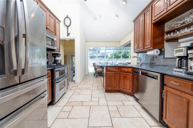 3458 Frederick St, Oceanside, NY 11572 - kitchen featuring stainless steel appliances, decorative backsplash, dark stone counters, vaulted ceiling, and brown cabinetry