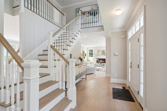 46 Plainview Rd, Woodbury, NY 11797 - foyer featuring stairs, a towering ceiling, ornamental molding, wood finished floors, and a lit fireplace