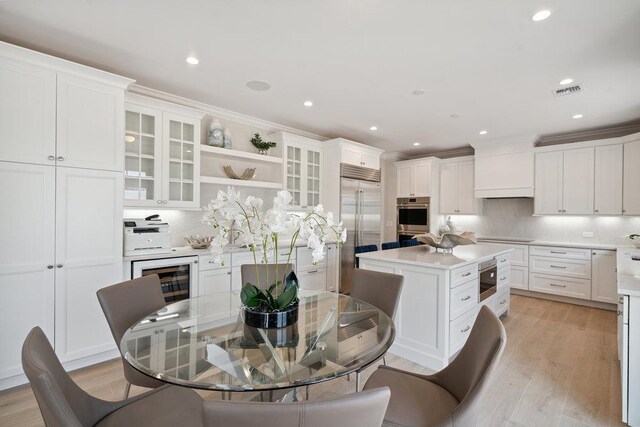 46 Plainview Rd, Woodbury, NY 11797 - kitchen with a kitchen island, built in appliances, white cabinets, wine cooler, and light countertops