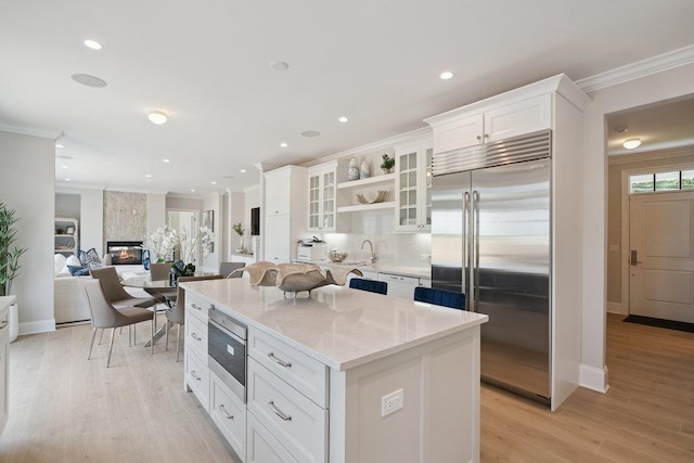 46 Plainview Rd, Woodbury, NY 11797 - kitchen featuring built in appliances, a center island, white cabinetry, ornamental molding, and glass insert cabinets