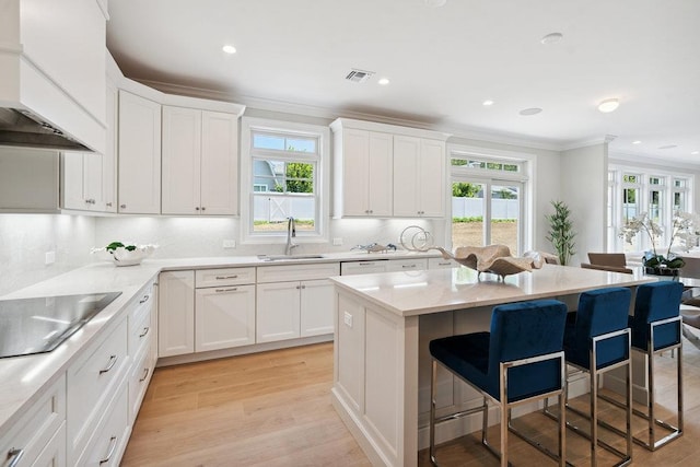 46 Plainview Rd, Woodbury, NY 11797 - kitchen featuring custom range hood, crown molding, a kitchen bar, black electric cooktop, and white cabinetry