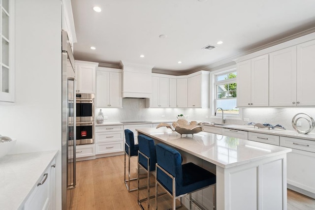 46 Plainview Rd, Woodbury, NY 11797 - kitchen with a breakfast bar, white cabinetry, a kitchen island, double oven, and black electric stovetop