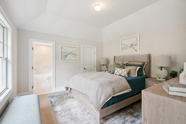 46 Plainview Rd, Woodbury, NY 11797 - bedroom featuring multiple windows, wood finished floors, vaulted ceiling, and ensuite bath