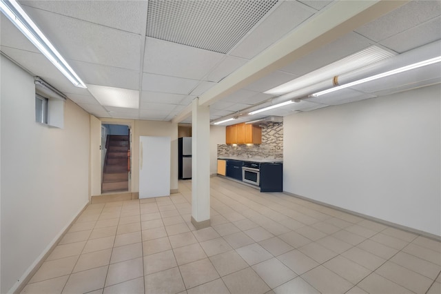 12605 109th Ave, Richmond Hill S, NY 11420 - finished below grade area with freestanding refrigerator, stairs, light tile patterned flooring, and a drop ceiling