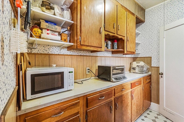 16608 Cryders Ln, Beechhurst, NY 11357 - kitchen featuring open shelves, white microwave, wallpapered walls, light countertops, and brown cabinetry