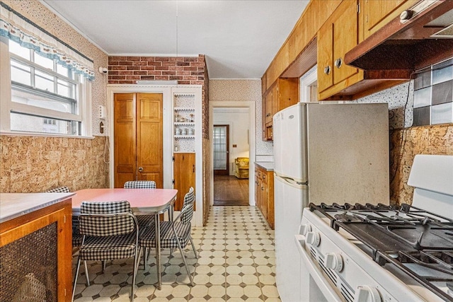 16608 Cryders Ln, Beechhurst, NY 11357 - kitchen featuring under cabinet range hood, white gas range, light flooring, wallpapered walls, and brown cabinets