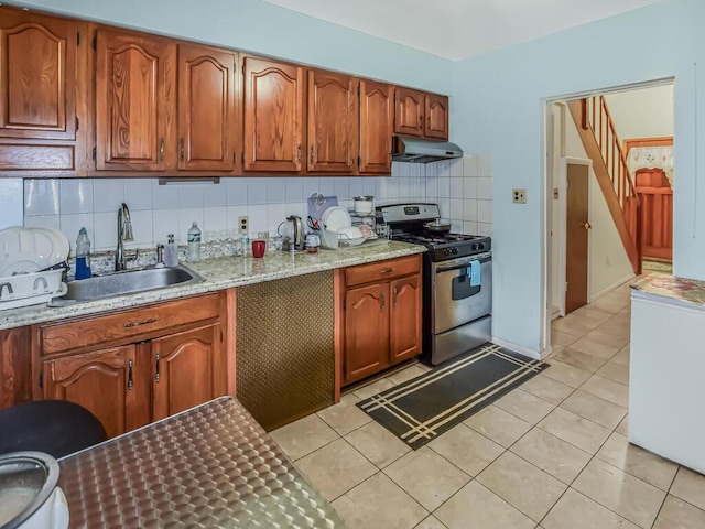 4431 Matilda Ave, Bronx, NY 10470 - kitchen featuring stainless steel range with gas cooktop, under cabinet range hood, tasteful backsplash, fridge, and brown cabinets