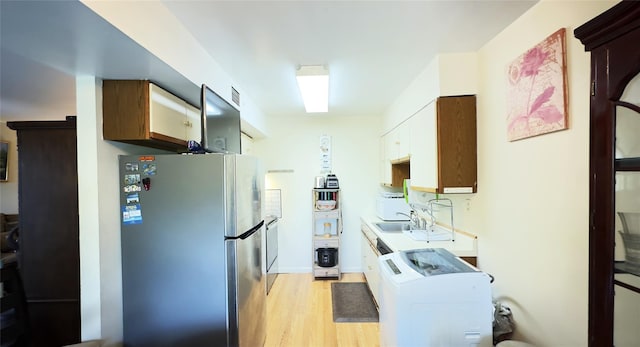 26 Cooper Unit 314, Poughkeepsie, NY 12603 - kitchen featuring freestanding refrigerator, washer / clothes dryer, light wood-style flooring, and light countertops