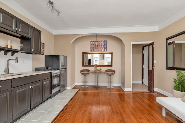 160-15 Powells Cove Blvd Unit A1, Whitestone, NY 11357 - kitchen with arched walkways, stainless steel gas stove, light countertops, light wood-style flooring, and ornamental molding