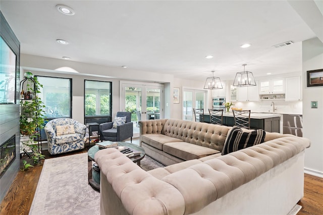 31 Boathouse Ln E, Bay Shore, NY 11706 - living area featuring recessed lighting, dark wood finished floors, a glass covered fireplace, a chandelier, and french doors