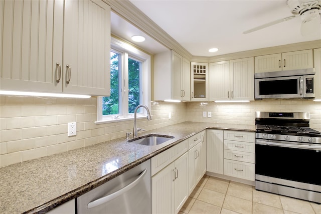 153 Park Ave, Manhasset, NY 11030 - kitchen with stainless steel appliances, light stone counters, glass insert cabinets, light tile patterned flooring, and decorative backsplash