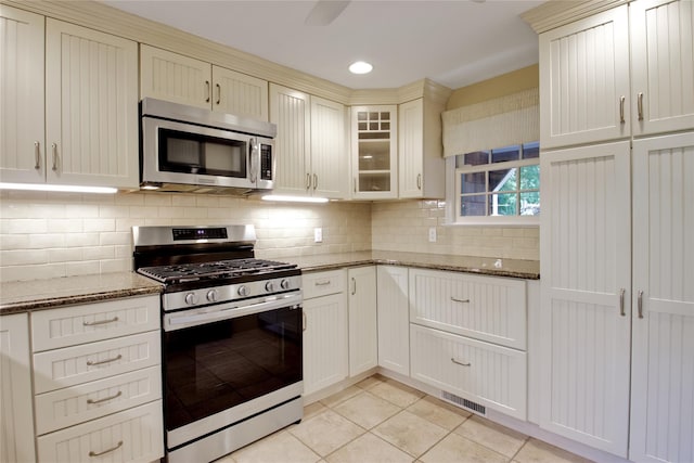 153 Park Ave, Manhasset, NY 11030 - kitchen with stainless steel appliances, light tile patterned flooring, stone countertops, tasteful backsplash, and glass insert cabinets