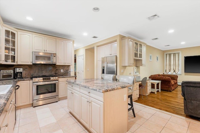 2 Apple Ct, Eastchester, NY 10709 - kitchen with stainless steel appliances, light tile patterned floors, open floor plan, glass insert cabinets, and a kitchen breakfast bar
