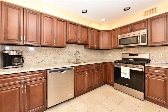 7 Albergo Ln, Syosset, NY 11791 - kitchen with stainless steel appliances, light tile patterned floors, light stone counters, tasteful backsplash, and brown cabinetry