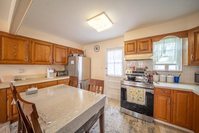 47 Cardinal Rd, Levittown, NY 11756 - kitchen featuring appliances with stainless steel finishes, under cabinet range hood, brown cabinets, light countertops, and tasteful backsplash
