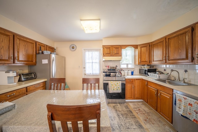 47 Cardinal Rd, Levittown, NY 11756 - kitchen with appliances with stainless steel finishes, under cabinet range hood, light countertops, brown cabinetry, and tasteful backsplash