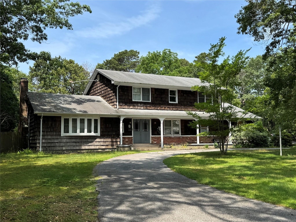 75 Topping Dr, Riverhead, NY 11901 - view of front of house with a front yard, curved driveway, a chimney, and a porch