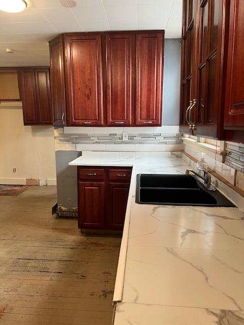 47 Gifford Ave, Poughkeepsie, NY 12601 - kitchen featuring light stone counters, reddish brown cabinets, wood-type flooring, and tasteful backsplash