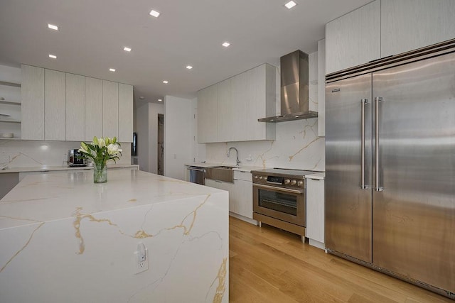 75 Red Fox Ln, Salt Point, NY 12578 - kitchen featuring appliances with stainless steel finishes, wall chimney exhaust hood, modern cabinets, light wood-style flooring, and backsplash