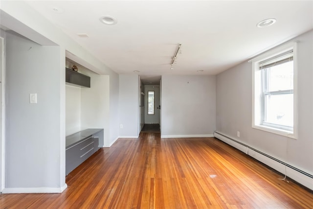 126 Tanglewylde Rd, Lake Peekskill, NY 10537 - unfurnished living room featuring a baseboard heating unit, healthy amount of natural light, track lighting, and hardwood / wood-style floors