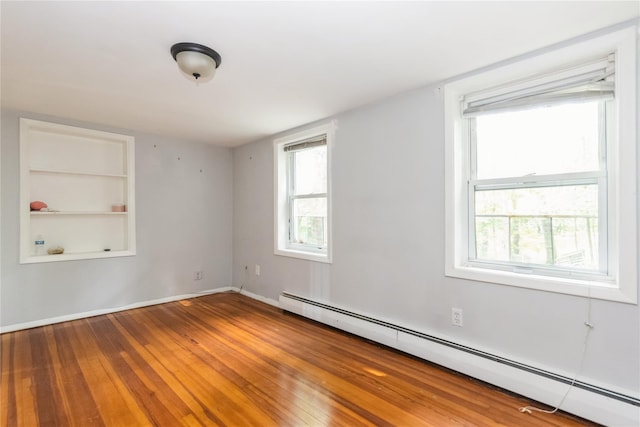 126 Tanglewylde Rd, Lake Peekskill, NY 10537 - unfurnished room featuring a baseboard heating unit, wood-type flooring, and built in features