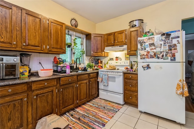 126 Tanglewylde Rd, Lake Peekskill, NY 10537 - kitchen featuring white appliances, under cabinet range hood, dark countertops, light tile patterned floors, and brown cabinets