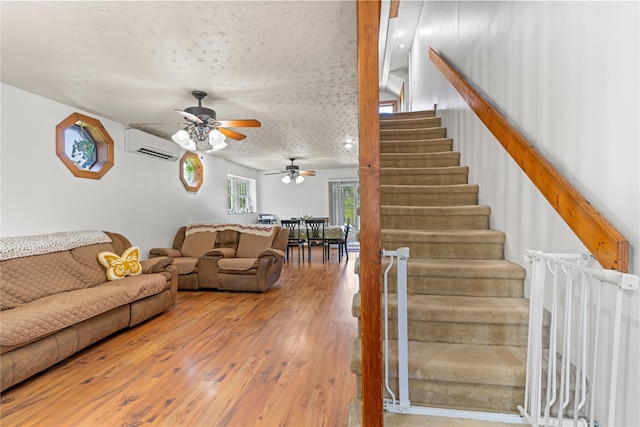 578 S St, Plattekill, NY 12528 - living area featuring a ceiling fan, stairs, a wall mounted air conditioner, wood finished floors, and a textured ceiling