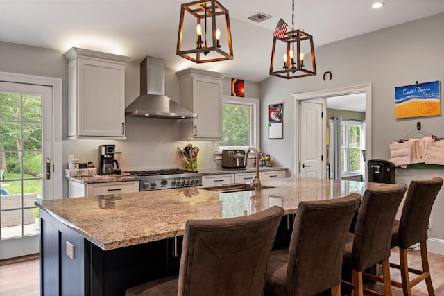 24 Canvasback Ln, East Quogue, NY 11942 - kitchen featuring wall chimney range hood, light stone counters, plenty of natural light, and recessed lighting