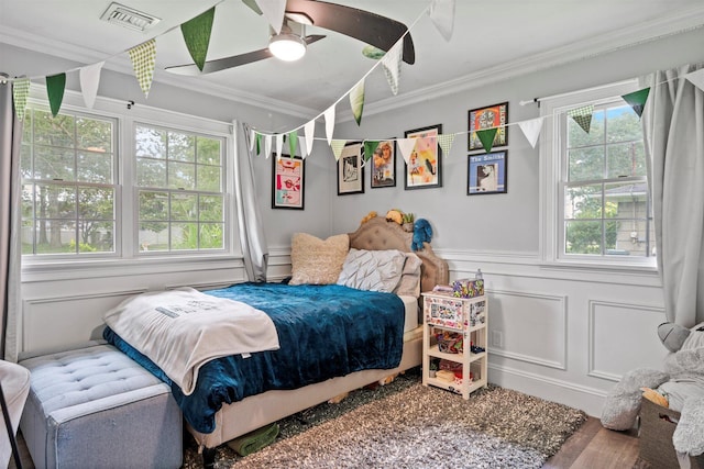 24 Canvasback Ln, East Quogue, NY 11942 - bedroom with a decorative wall, crown molding, wood finished floors, a wainscoted wall, and ceiling fan