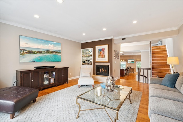 28 The Mews, Syosset, NY 11791 - living area featuring light wood finished floors, recessed lighting, ornamental molding, stairway, and a glass covered fireplace