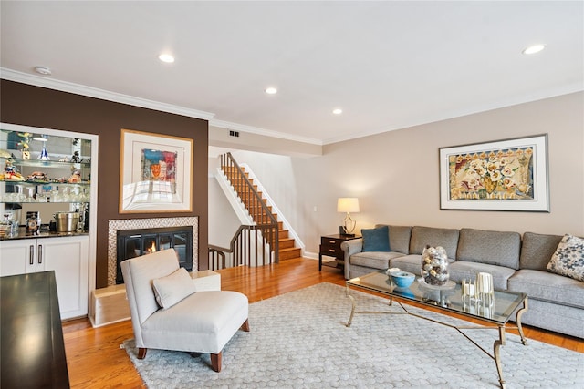 28 The Mews, Syosset, NY 11791 - living room featuring light wood finished floors, ornamental molding, stairway, a glass covered fireplace, and recessed lighting