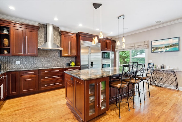 28 The Mews, Syosset, NY 11791 - kitchen featuring wall chimney range hood, built in appliances, a center island, dark stone counters, and tasteful backsplash