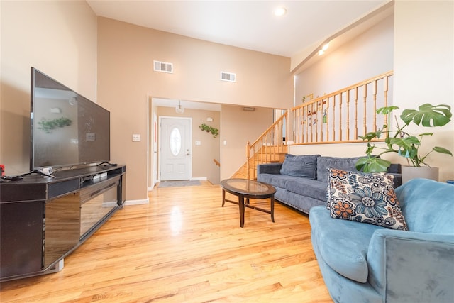 98 Virginia Ave, Plainview, NY 11803 - living area with stairs, light wood-type flooring, and a towering ceiling