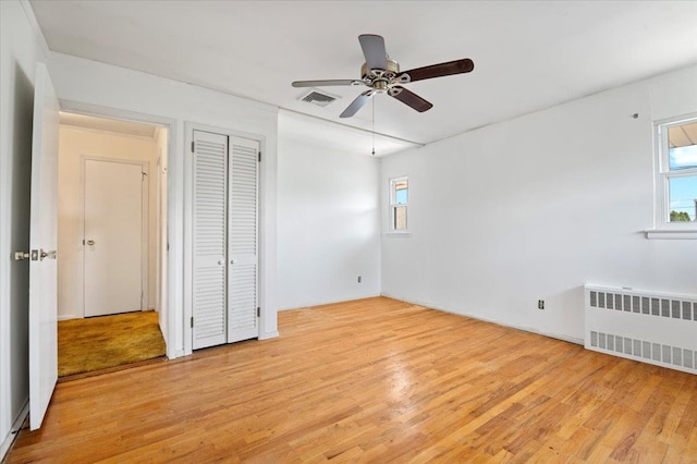 20 Deb St, Plainview, NY 11803 - unfurnished bedroom with radiator heating unit, light wood-style floors, ceiling fan, and a closet