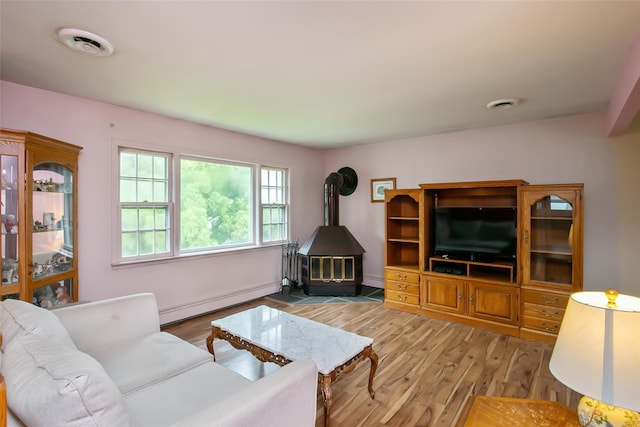 180 Hunter Ave, North Babylon, NY 11703 - living area featuring a baseboard heating unit, a wood stove, and light wood-style flooring