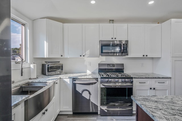 15 Aron Dr, Bohemia, NY 11716 - kitchen with stainless steel appliances, white cabinetry, light stone countertops, wood finished floors, and recessed lighting