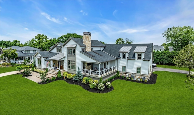 52 Concourse E, Brightwaters, NY 11718 - back of house featuring a chimney, a yard, a standing seam roof, and roof with shingles