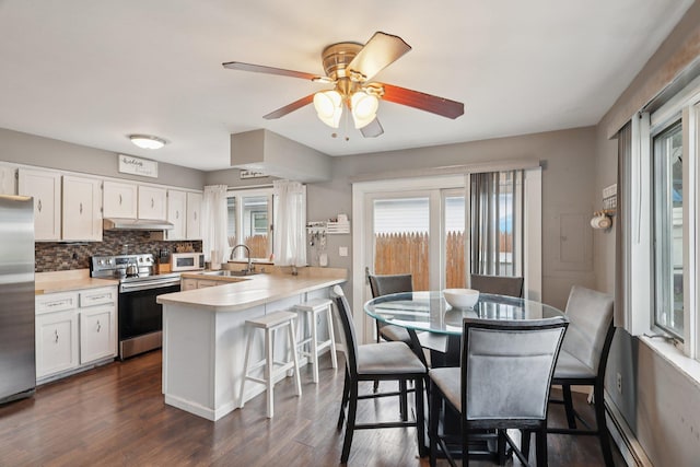17 Lombardy Dr, Shirley, NY 11967 - kitchen featuring appliances with stainless steel finishes, a baseboard heating unit, under cabinet range hood, a peninsula, and plenty of natural light